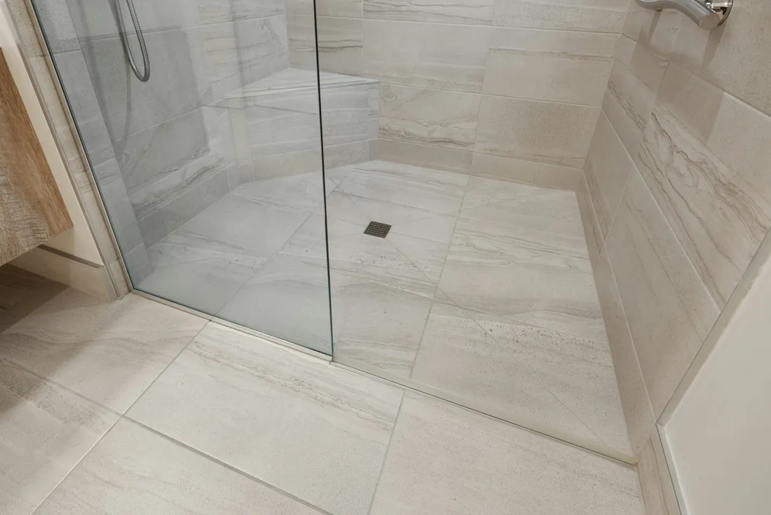 Sol de douche de plain-pied carrelé dans la continuité de la salle de bain, avec siphon, paroi vitrée fixe et barre d'appui au mur (Saint-Thégonnec Loc-Eguiner, Finistère)